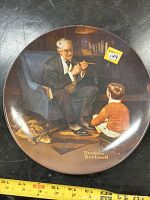 Front of the collector plate showing the detailed Norman Rockwell image of an elderly man with a pipe and a child on a rug with a dog under a chair.