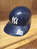 Front angled view of blue plastic helmet with New York Yankees logo on front.