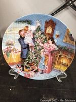 Front of the collector plate showing a Victorian Christmas scene of a family decorating a tree and a fireplace.