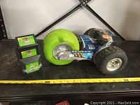 Side view of the Tyco radio controlled car showing oversized green foam front tire and black rear tire with silver rims, along with two black battery chargers or battery compartments.