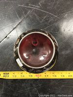 Top view showing round red glass dish with silver floral and grapevine overlay decoration and measuring tape indicating approximately 5 inch diameter.