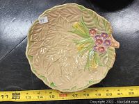 Top view of the leaf-shaped plate showing floral and leaf embossed design with color accents. Includes measurement of approximately 9 inches in width.