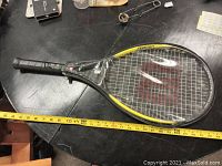 Full view of Wilson tennis racquet showing length with measuring tape, black and yellow frame, and black grip