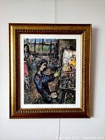 Framed lithograph of colorful interior scene with artist and standing woman holding flowers, titled and signed by Marc Chagall.