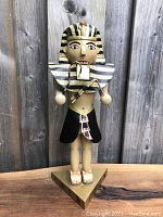 Front view of 14-inch wooden Egyptian Pharaoh nutcracker with striped gold and black headdress and painted detailed face and attire.