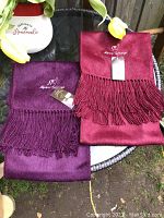 Two scarves folded with visible fringe and embroidered Alpaca Camargo logo, one burgundy and one wine color