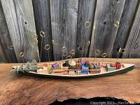 Front view of the full ceramic canoe card holder with Christmas trees, gifts, and card holding loops visible.