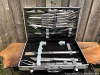 Open carrying case displaying 23-piece set of BergHOFF barbecue utensils including forks, knives, picks, basting brush, and salt/pepper shakers.