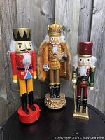 Three large wooden nutcrackers side by side showing size, colors, and details