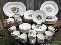 Lot overview showing entire 43-piece Sonata Noel Christmas dish set with serving pieces displayed on wooden table outdoors.