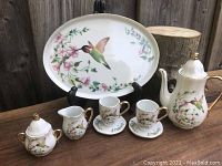 Full view of miniature tea set on oval tray featuring hummingbird and floral design, including teapot, sugar bowl, creamer, cups, and saucers.