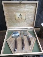 Open wooden box showing Laguiole 3 cheese utensils on the hexagonal wood tray, secured in plastic inserts.