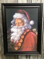 Close-up of the large framed painting of Santa Claus by Susan Cornish showing detailed brushwork, Santa in red suit with white beard and gold jingle bells.