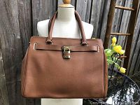 Front view of the brown pebbled leather briefcase tote with double handles and padlock on front strap.