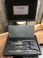 Full view of the set in black presentation box with stone cheese tray raised above knives