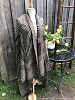 Full view of the wool shawl wrap on a mannequin, highlighting its length and drape outdoors.