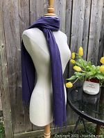 Front view of the deep purple cashmere scarf wrapped around a mannequin, showing the scarf's color and texture with fringed ends hanging down.