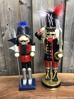 Both large and smaller French mustache nutcracker figurines standing together with detailed attire and accessories.