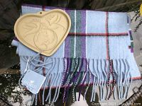 Scarf folded with attached tags and heart-shaped cookie mold on top showing peace themed design
