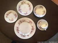 One place setting with dinner plate, salad plate, bowl, cup and saucer on table