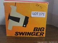 Photo of the original bright orange box with bold black 'Big Swinger' text and camera illustration, showing some wear but intact.