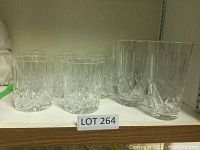 Ten clear crystal glasses on shelf, 5 shorter tumblers and 5 taller highball glasses, all with cut designs visible