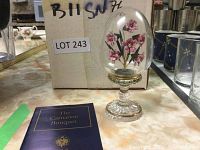 Crystal dome containing the pink carnation bouquet on a crystal pedestal base next to original box and booklet on countertop