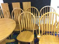 Photo of 2 oak armchairs and 4 oak side chairs with spindle backs arranged near a matching oak table, showing overall set condition and design.