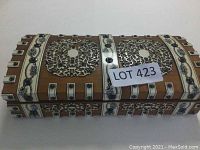 Top-front angled view of the ornately decorated wooden game box showing elaborate inlay patterns and metal studding.