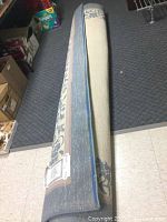 Rolled view of the rug showing pattern colors and condition, minor damage on one edge visible.