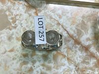 Silver tone condiment holder with two glass containers and lid taken from top angle showing LOT 257 tag.