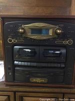 Front view of wooden cabinet stereo with control panel, display, dual cassette decks and Nostalgia branding