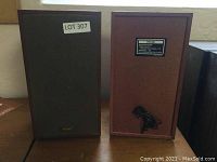 Pair of TEAC vintage speakers, one showing front with fabric grill and logo, the other showing rear with TEAC label and cables wrapped.