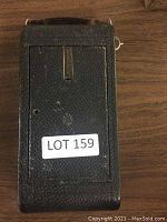 Vintage Kodak camera in black textured leatherette case with metal detailing, showing signs of wear.