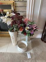 Wide view showing both artificial flower arrangements and planter on floor near fireplace.