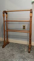 Full frontal view of wooden blanket rack against wall with carpeted floor