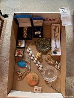 Image showing entire assortment of costume jewelry and accessories in a box, including bracelets, necklaces, brooches, pins, earrings, makeup mirror, ring holders