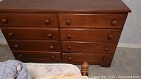 Front view of wooden dresser showing all eight drawers and round wooden knobs.