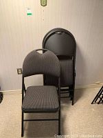 Front and stacked view of four folding chairs showing padded seats and backrests.