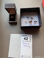 Overview of all seven rings displayed in wood box and black tray