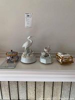 Wide front view of four music boxes: a piano, two bird figures, and a rectangular box with gold trim