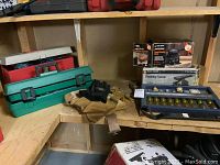 Overview of the lot showing green Sears Craftsman rotary tool case, Makita toolbox, carpenter's pouch with gloves, wood chisels, pry bar, and Black & Decker sanding tools.