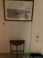 Front view of wall showing the framed Toronto downtown ink drawing and demi lune table below.