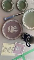 Six Wedgwood Jasper pieces including a limited edition Valentine's Day 1982 plate, two green ashtrays, a green plate, a blue and white mug, and a knife with blue handle.