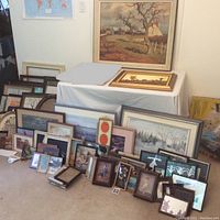 Overall view of approximately 30 framed art pieces on floor and table