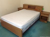 Double bed shown with mattress and two nightstands on either side. The bed has a built-in shelf in the headboard and tapered feet.