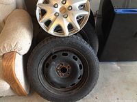 Stacked steel wheel rims with mounted tires and one plastic hubcap visible
