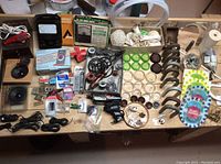 Wide view of assorted items including meters, magnets, cables, soldering supplies and storage box on a wooden table