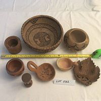Full view of all items including Hopi-Tewa pottery, Nigerian calabash, carved duck, and various smaller pottery pieces arranged with tape measure for scale.