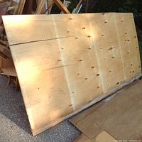 Large plywood sheet showing knots, cracks, and water damage